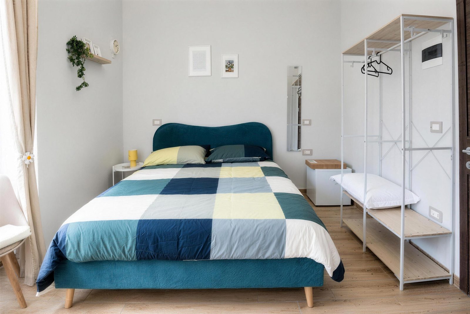 La camera doppia del Fuoribinario B&B: letto matrimoniale con testiera ottanio e copriletto a quadri colorati